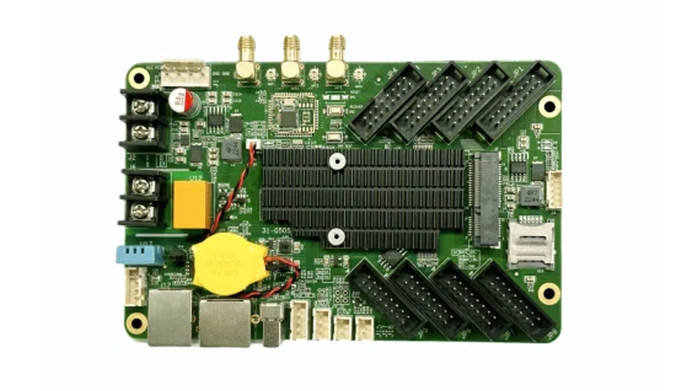 Green development board with a large black heatsink, yellow coin-cell battery, USB ports, and multiple edge connectors.