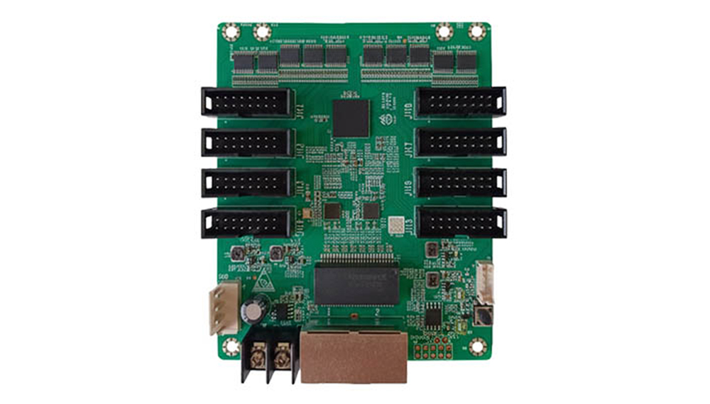 Green PCB expansion board with eight black edge connectors (four on each side), a central processor, and a brown connector at the bottom; various small components scattered across the board.