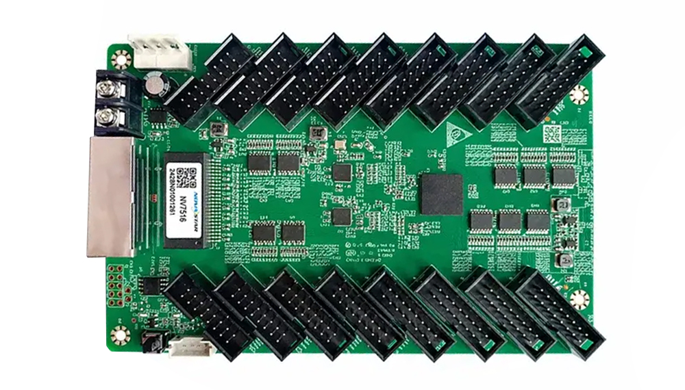 Green development board with two rows of angled black header pins and a metal module on the left side.