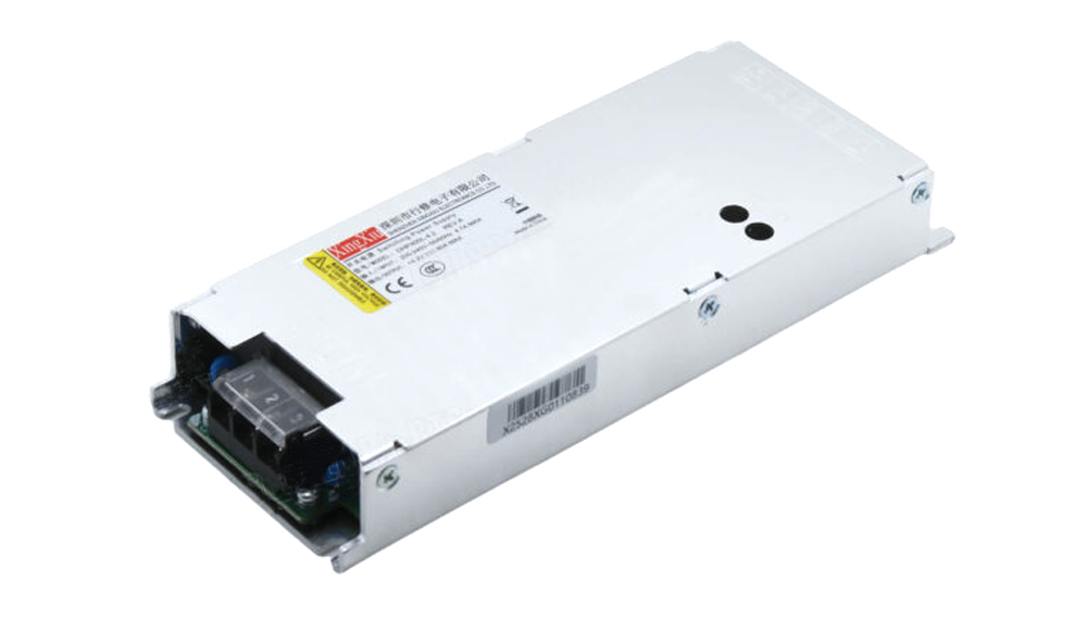 White metal industrial switching power supply seen from an angled perspective, with exposed terminals and labels on top side