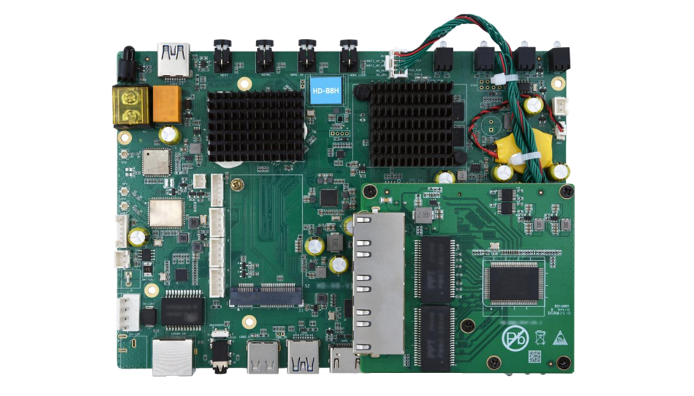 Green single-board computer motherboard with heatsinks, RAM, connectors, and power components visible on a white background.